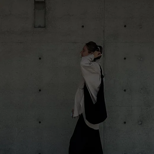A figure walking through a quiet concrete corridor, taking the first step